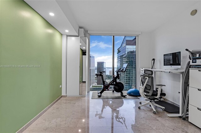 exercise area featuring light tile flooring and a wall of windows