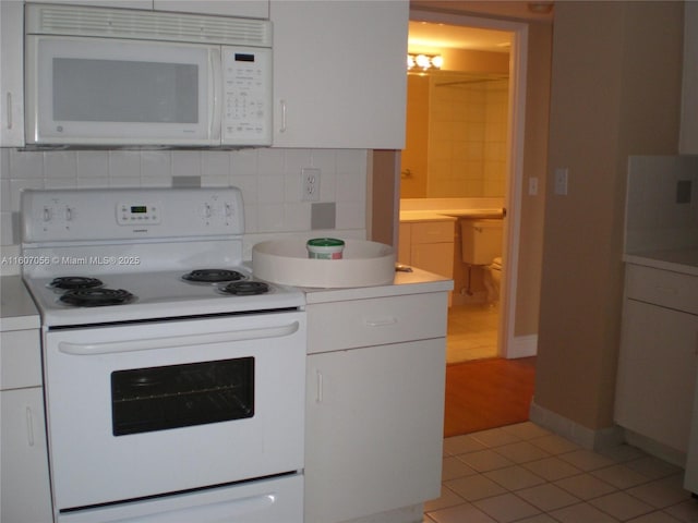 kitchen featuring light tile patterned flooring, white appliances, white cabinets, and backsplash