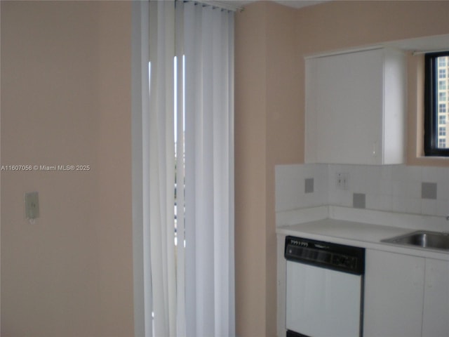 kitchen with sink, white cabinetry, white dishwasher, and tasteful backsplash