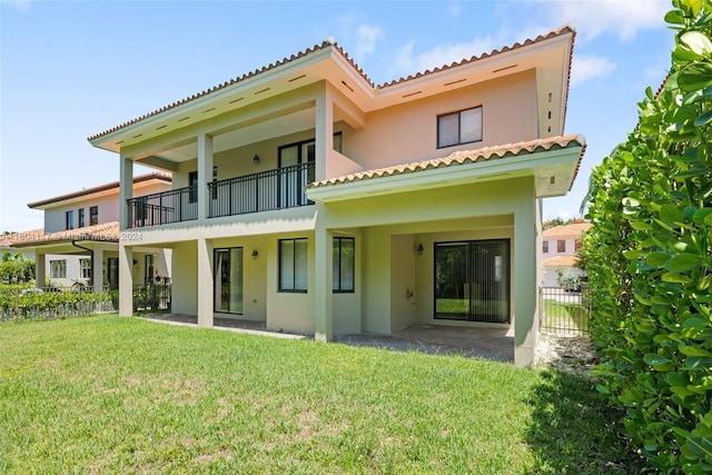 back of house featuring a balcony and a lawn