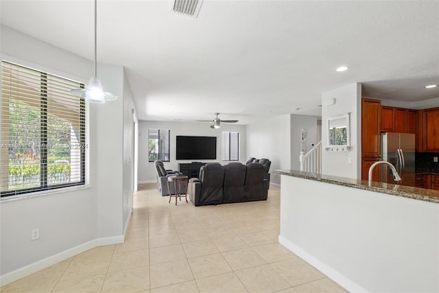 kitchen with dark stone counters, ceiling fan, light tile patterned floors, stainless steel fridge with ice dispenser, and hanging light fixtures