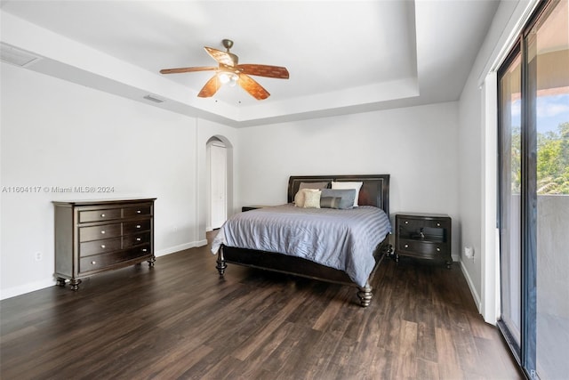 bedroom featuring a raised ceiling, ceiling fan, dark hardwood / wood-style floors, and access to outside