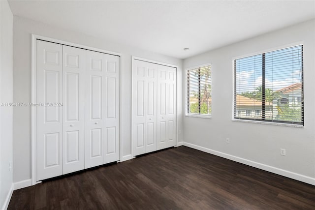 unfurnished bedroom featuring dark hardwood / wood-style flooring and multiple closets