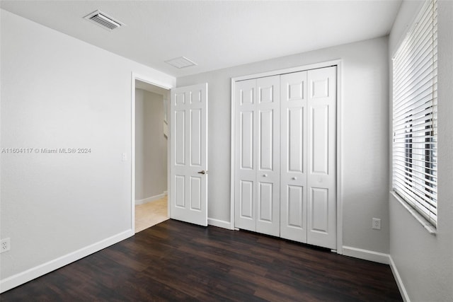 unfurnished bedroom featuring dark wood-type flooring and a closet