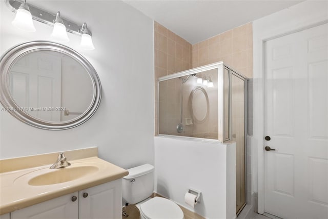 bathroom featuring vanity, a shower with shower door, and toilet