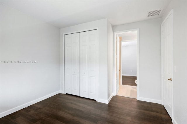 unfurnished bedroom with dark hardwood / wood-style floors and a closet