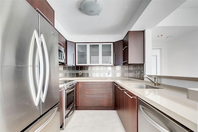 kitchen with stainless steel appliances, dark brown cabinets, sink, and backsplash