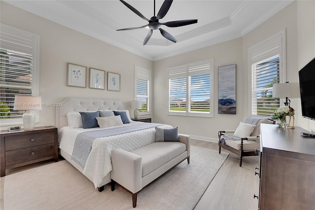 bedroom featuring a raised ceiling, multiple windows, ceiling fan, and light hardwood / wood-style floors