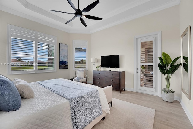 bedroom with crown molding, a raised ceiling, ceiling fan, and light wood-type flooring