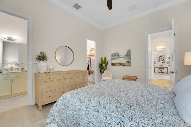 bedroom with crown molding, ensuite bath, ceiling fan, a walk in closet, and a closet