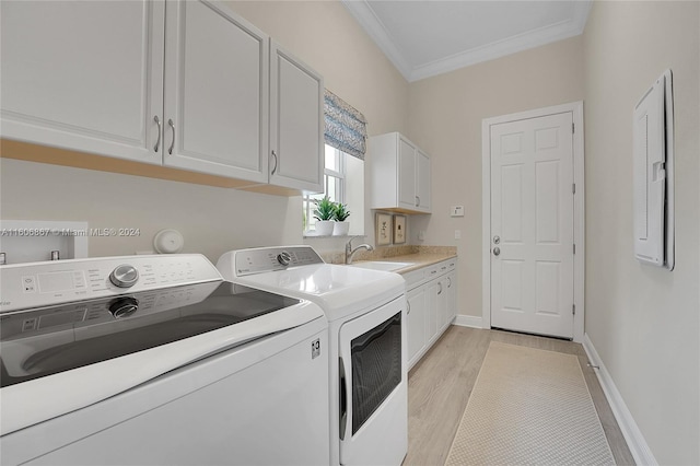 laundry area with sink, cabinets, washer and dryer, light hardwood / wood-style flooring, and ornamental molding