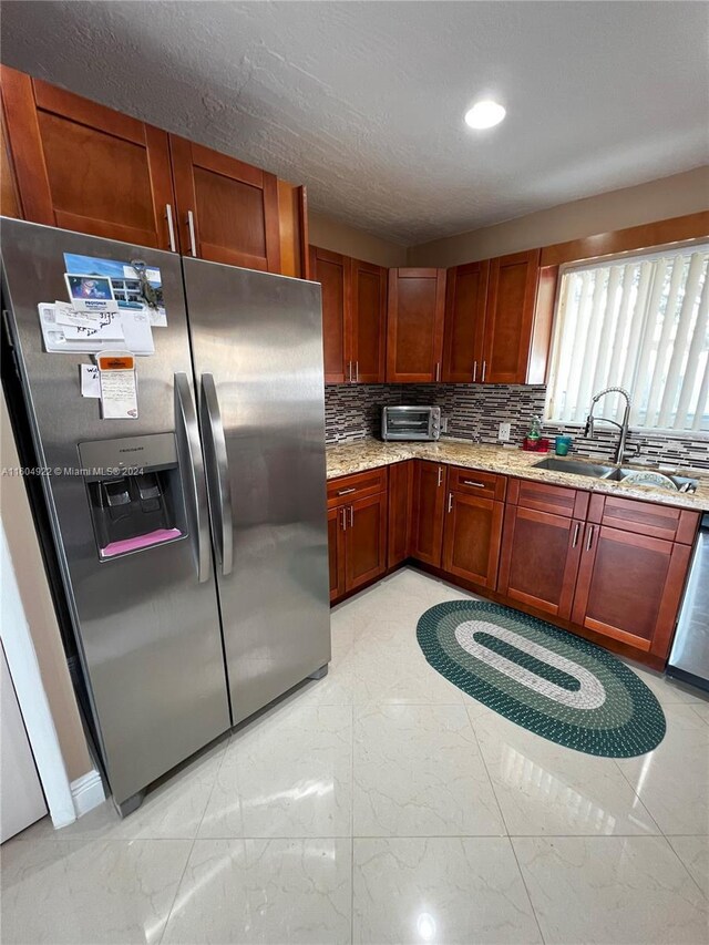 kitchen with tasteful backsplash, dishwasher, light tile flooring, stainless steel refrigerator with ice dispenser, and sink