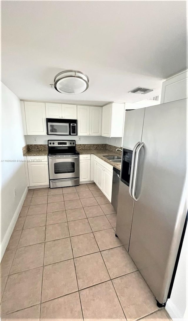 kitchen featuring sink, white cabinets, light tile patterned floors, and appliances with stainless steel finishes