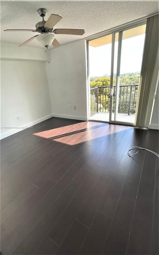 spare room with ceiling fan, expansive windows, and dark hardwood / wood-style floors