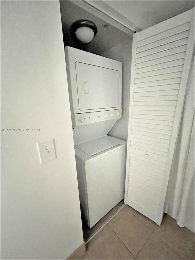 laundry area with stacked washer / drying machine and light tile patterned floors