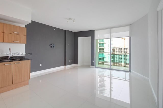 spare room with light tile patterned flooring, expansive windows, and sink