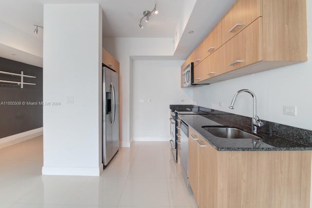 kitchen featuring light tile patterned floors, dark stone counters, modern cabinets, stainless steel appliances, and a sink