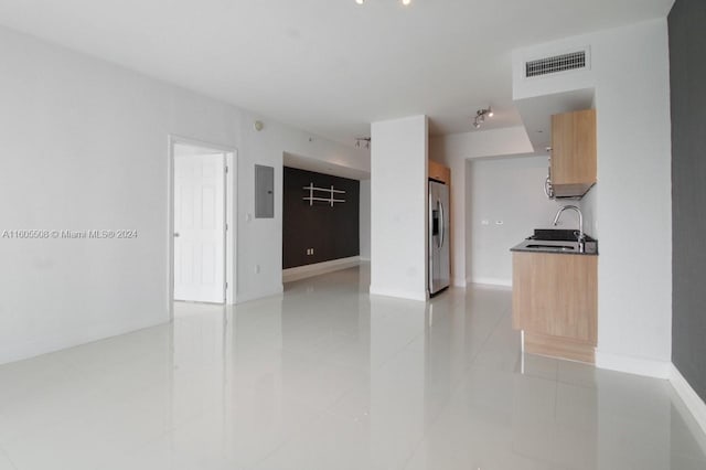 interior space with light tile patterned floors, a sink, visible vents, baseboards, and electric panel