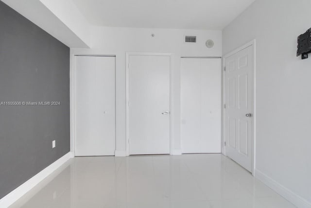 unfurnished bedroom featuring baseboards, visible vents, and tile patterned floors