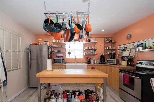 kitchen featuring open shelves, stainless steel appliances, a sink, wood counters, and light wood-type flooring