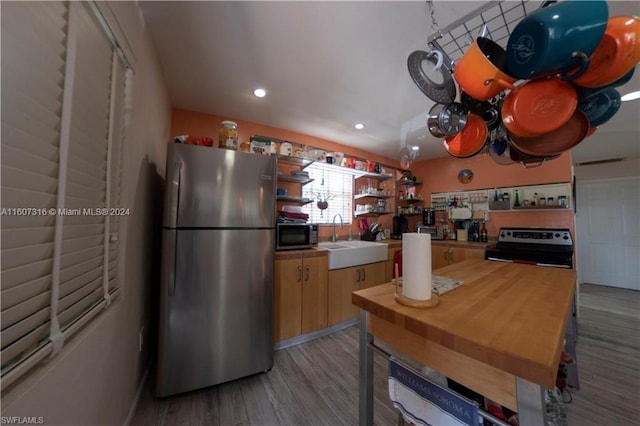 kitchen with light wood finished floors, open shelves, recessed lighting, appliances with stainless steel finishes, and a sink