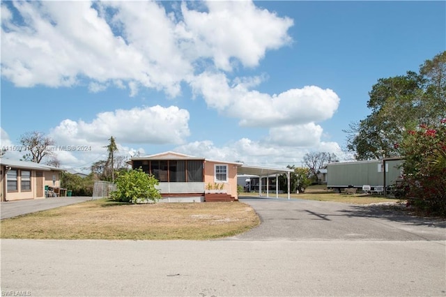 manufactured / mobile home featuring an attached carport, a sunroom, and aphalt driveway