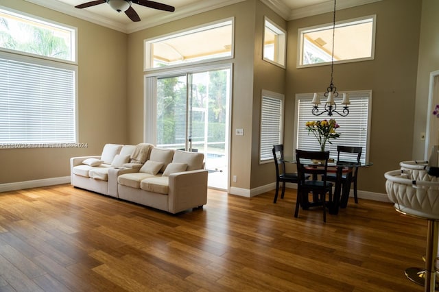 living room with a wealth of natural light, ceiling fan with notable chandelier, and hardwood / wood-style flooring