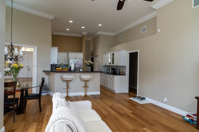 kitchen with white fridge, light hardwood / wood-style flooring, ceiling fan, white cabinetry, and ornamental molding