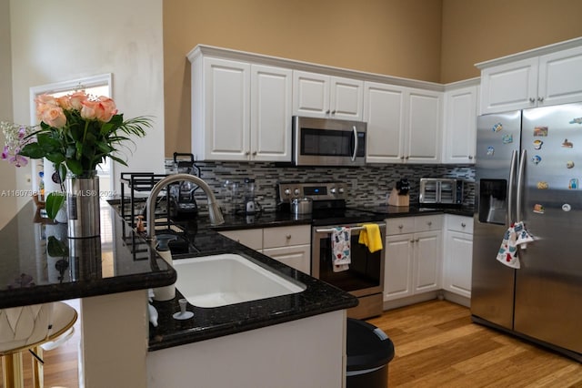 kitchen featuring stainless steel appliances, white cabinets, light hardwood / wood-style flooring, and kitchen peninsula