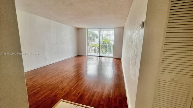 spare room with hardwood / wood-style flooring, a wall of windows, and a textured ceiling