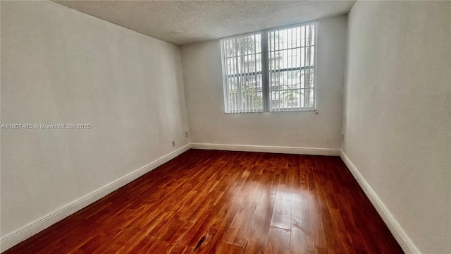 unfurnished room featuring dark hardwood / wood-style floors and a textured ceiling