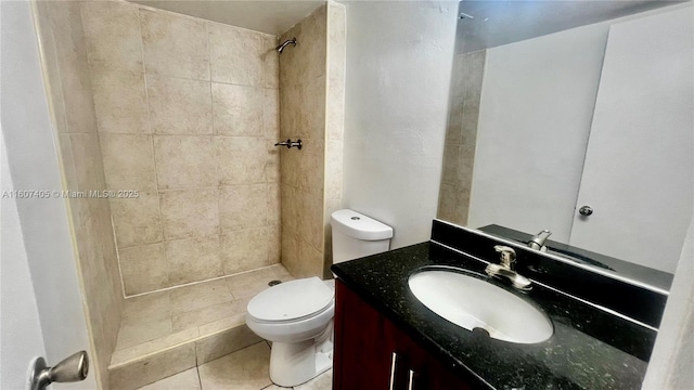 bathroom featuring vanity, a tile shower, tile patterned floors, and toilet