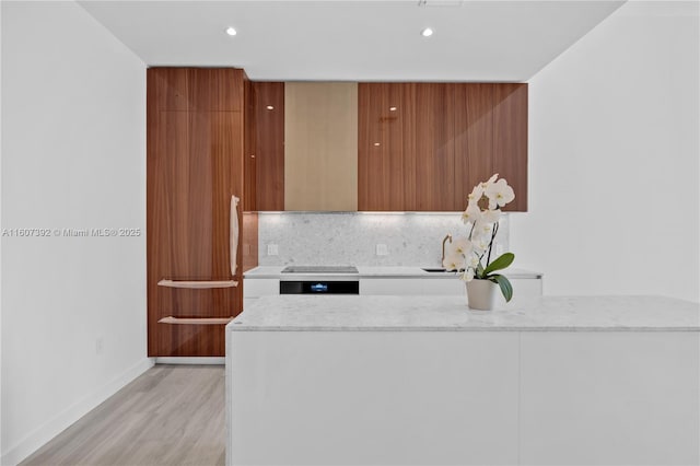 kitchen with sink, light hardwood / wood-style flooring, wall oven, light stone countertops, and decorative backsplash