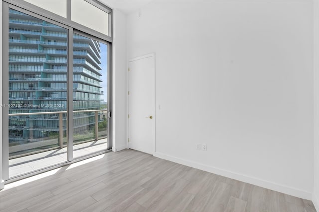 spare room with floor to ceiling windows and light hardwood / wood-style floors