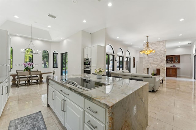 kitchen with black electric stovetop, decorative light fixtures, a kitchen island, and white cabinetry