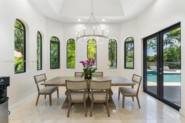 dining space with a towering ceiling, light tile patterned flooring, and an inviting chandelier