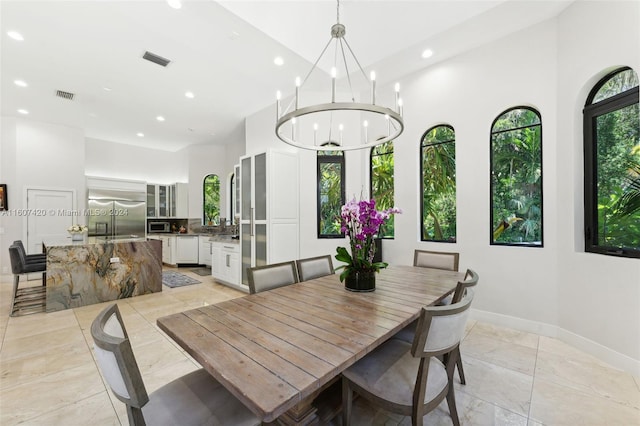 dining area featuring a towering ceiling and a notable chandelier