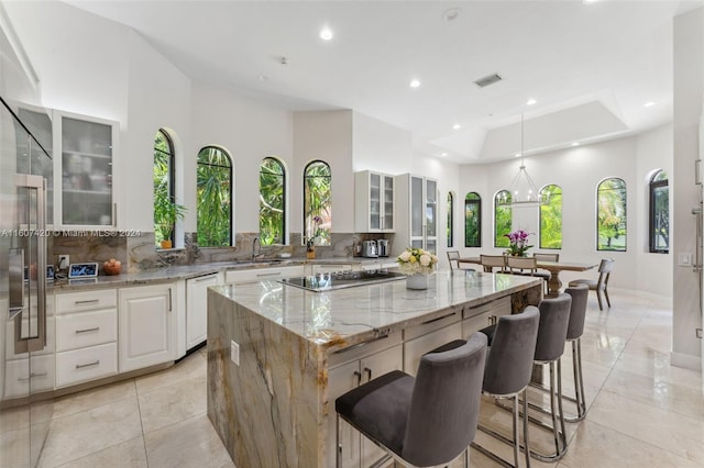 kitchen featuring tasteful backsplash, light stone counters, a center island, and stainless steel gas cooktop