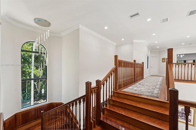 stairway featuring crown molding, a healthy amount of sunlight, and wood-type flooring