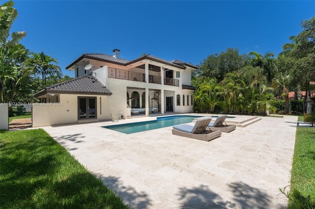 rear view of house with french doors, a patio, a balcony, and a fenced in pool