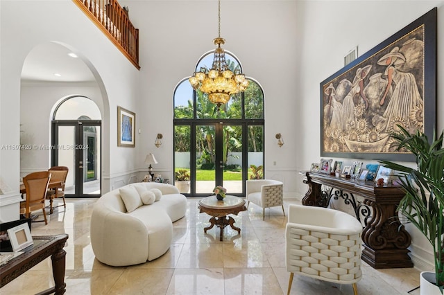 living area featuring french doors, an inviting chandelier, a high ceiling, and ornamental molding