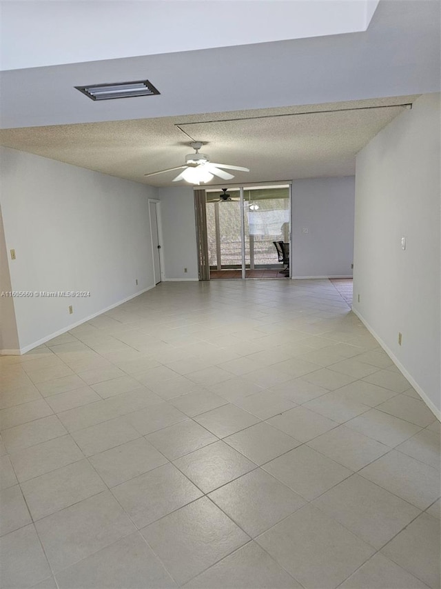 tiled spare room featuring floor to ceiling windows, ceiling fan, and a textured ceiling