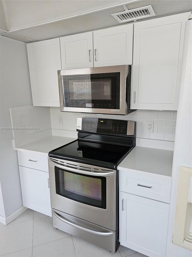 kitchen with appliances with stainless steel finishes, white cabinets, and backsplash