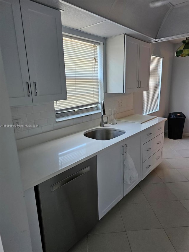 kitchen featuring white cabinets, sink, stainless steel dishwasher, and light tile floors