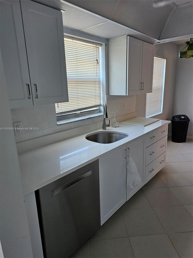 kitchen with light tile patterned floors, a sink, decorative backsplash, light countertops, and dishwasher