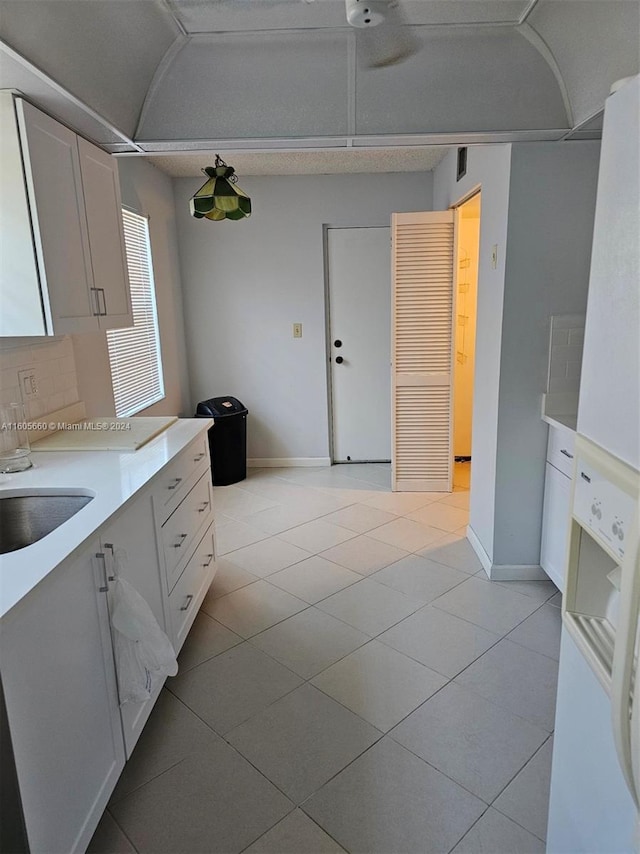 kitchen with sink, white cabinets, and light tile flooring