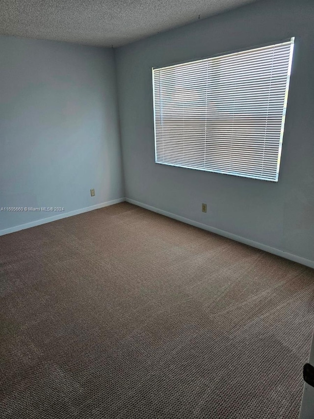 carpeted spare room featuring a textured ceiling