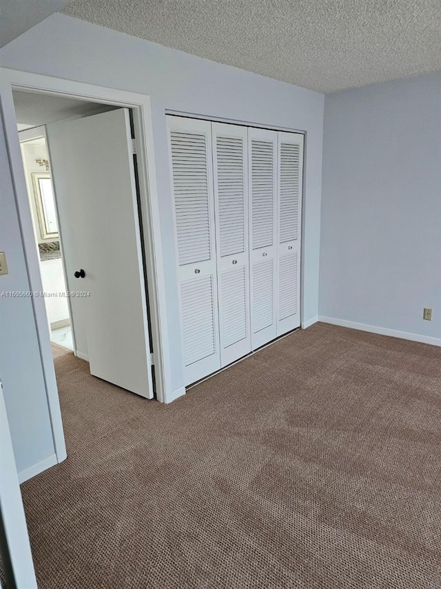 unfurnished bedroom featuring dark colored carpet, a closet, and a textured ceiling