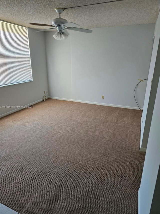 spare room with a textured ceiling, carpet floors, and ceiling fan