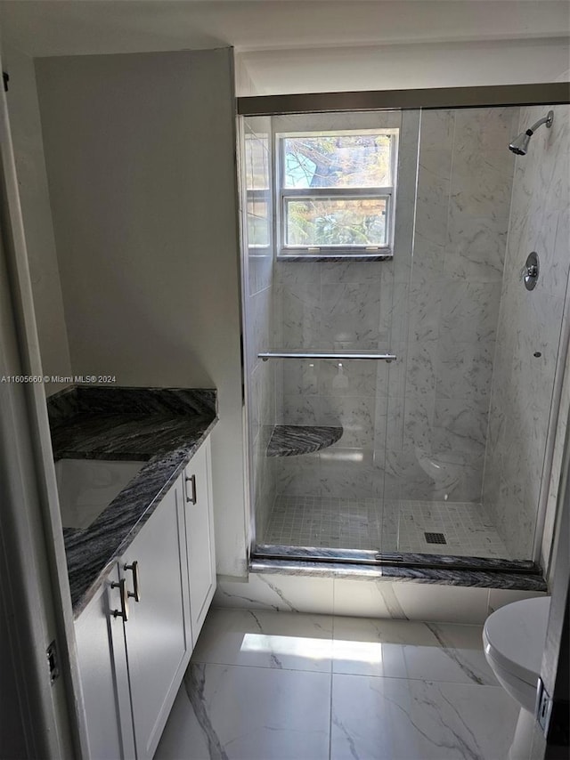 bathroom featuring toilet, marble finish floor, a stall shower, and vanity